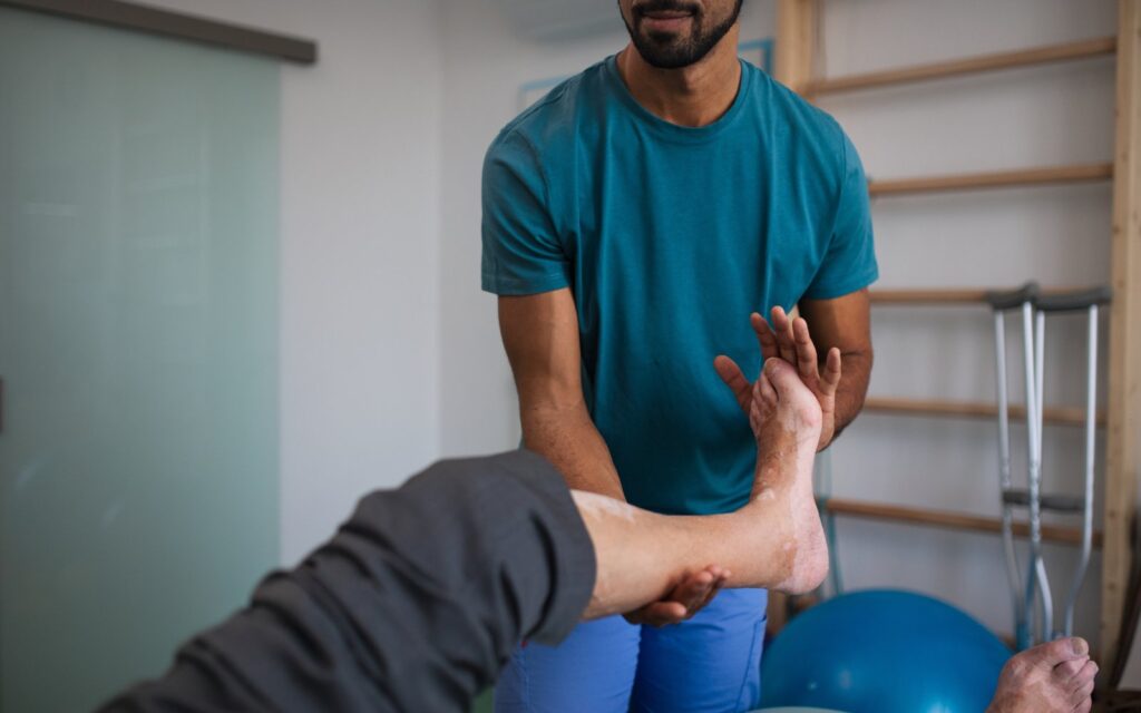 Physiotherapist exercising with senior patient's leg