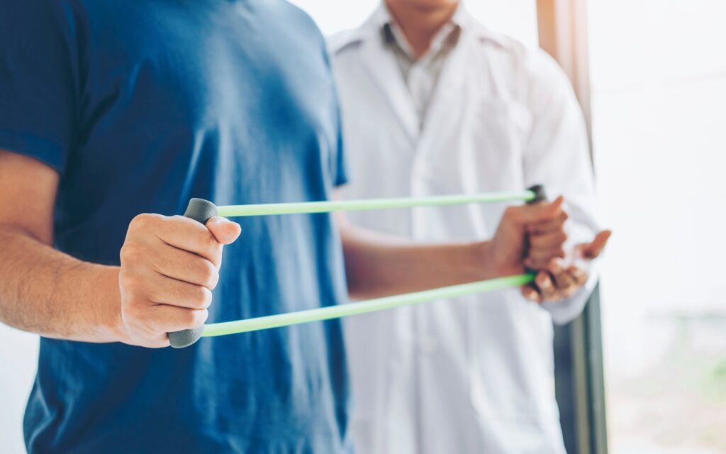 Physiotherapist man giving resistance band exercise treatment